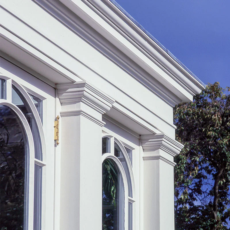 Elegant white conservatory with arched windows, classical columns and detailed roof cornicing