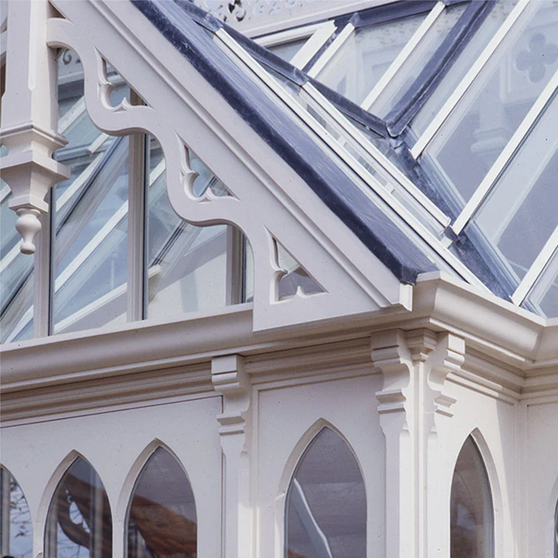 Ornate Victorian conservatory with Gothic arched windows, decorative timber fretwork and glazed roof